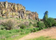 At hike's end is a flowing stream beneath shade trees and colorful basalt cliffs.